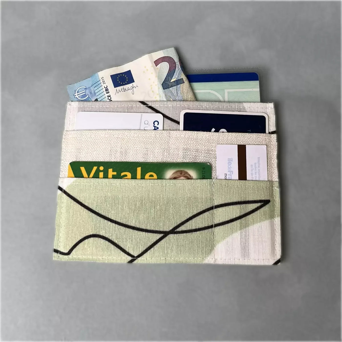 Porte-Cartes Essentiel'Slim CATASTROFF vert pâle avec motifs noirs, contenant cartes et billets.