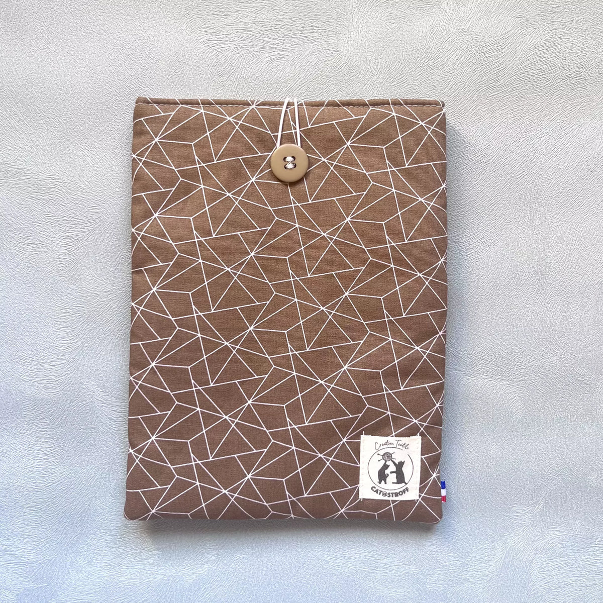 Pochette à livre marron ligné Puzzle Café vue de face, motif géométrique blanc sur coton brun, bouton de récupération assorti, étiquette Catastroff.