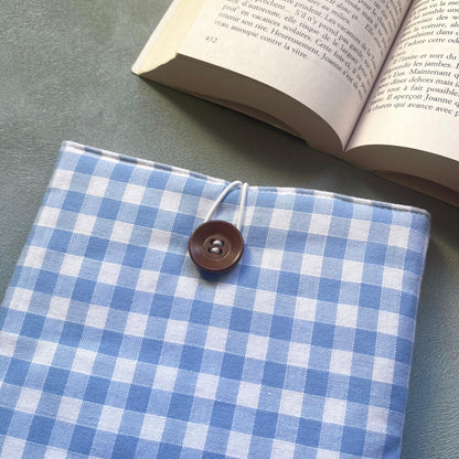 Gros plan sur la fermeture élastique et bouton de récupération en bois brun de la pochette livre tissu vichy bleu clair
