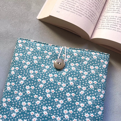 Gros plan sur la fermeture élastique et bouton de récupération de la pochette livre tissu fait main, motif pâquerettes blanches et cœurs roses bien visibles.