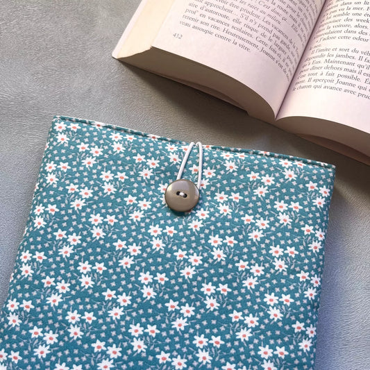 Gros plan sur la fermeture élastique et bouton de récupération de la pochette livre tissu fait main, motif pâquerettes blanches et cœurs roses bien visibles.