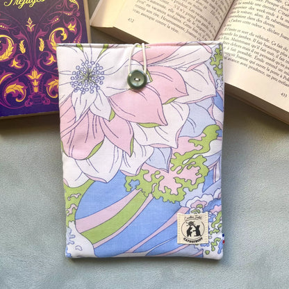 Pochette à livre en coton fleuri pastel upcyclé avec bouton de récupération vert, ici posé sur un livre ouvert