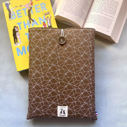 Pochette à livre grand format Cacao Graphique posée avec un roman broché et un livre ouvert, illustrant son usage au quotidien