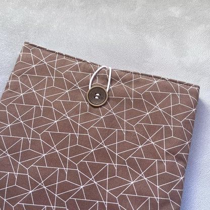 Gros plan sur la fermeture élastique et bouton chiné de la pochette livre tissu fait main, détail du coton cacao et des coutures soignées