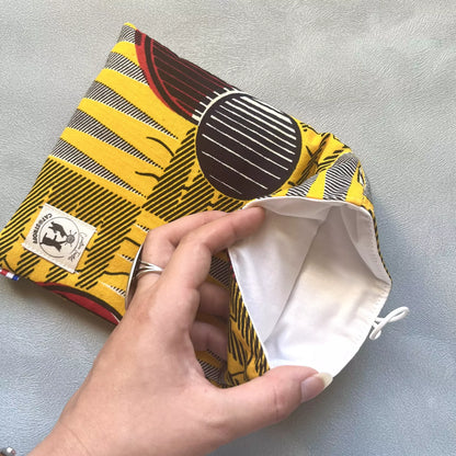 Pochette livre de poche en tissu wax africain jaune et noir, intérieur en coton blanc visible sur l'image, faite main par Catastroff