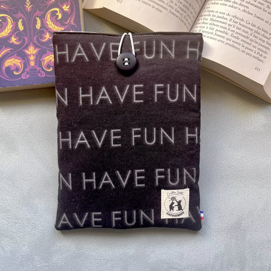 Pochette à livre upcyclés noir motif Have Fun, cousue main, vue recto avec bouton de récupération et posé sur un livre ouvert